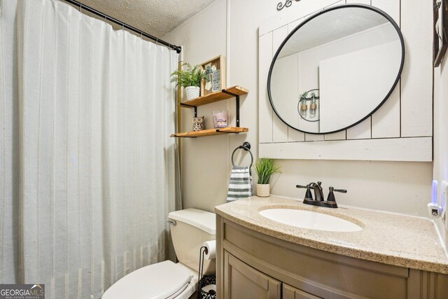 bathroom with vanity, toilet, and a textured ceiling