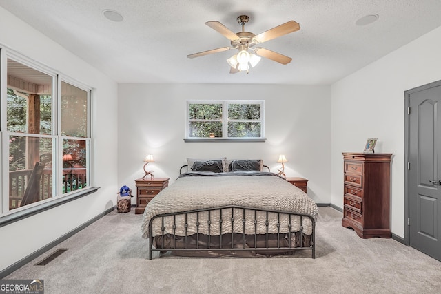 bedroom featuring light carpet, ceiling fan, and a textured ceiling