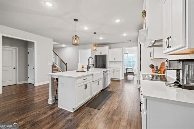 kitchen with decorative light fixtures, dishwasher, white cabinets, dark hardwood / wood-style flooring, and a kitchen island with sink