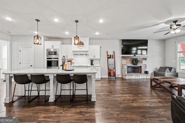 kitchen featuring a breakfast bar area, white cabinets, hanging light fixtures, stainless steel appliances, and a spacious island