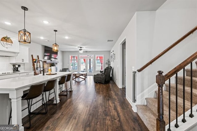 kitchen with pendant lighting, a breakfast bar, tasteful backsplash, white cabinets, and dark hardwood / wood-style flooring