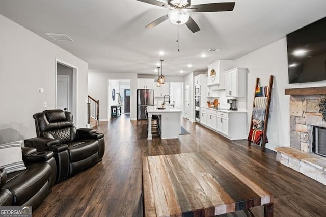 living room featuring sink, a fireplace, dark hardwood / wood-style floors, and ceiling fan