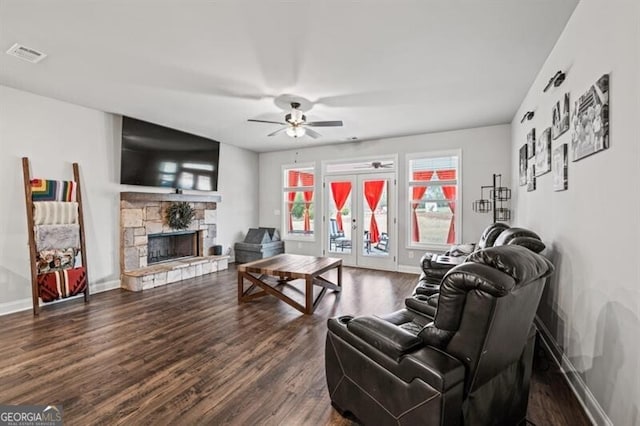 living room with a fireplace, dark wood-type flooring, french doors, and ceiling fan