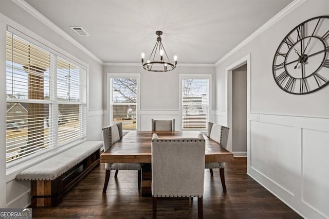 dining area with an inviting chandelier, ornamental molding, and dark hardwood / wood-style flooring