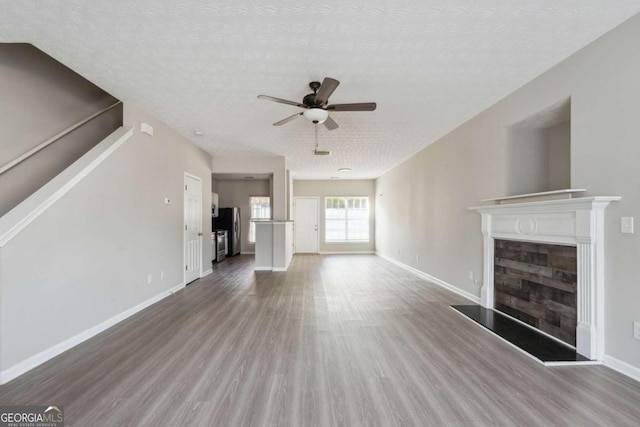 unfurnished living room featuring ceiling fan, hardwood / wood-style floors, and a textured ceiling