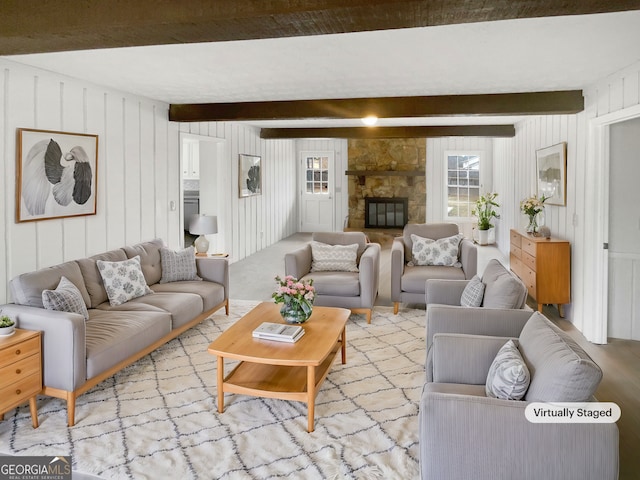 living room with beamed ceiling, a stone fireplace, and light hardwood / wood-style flooring