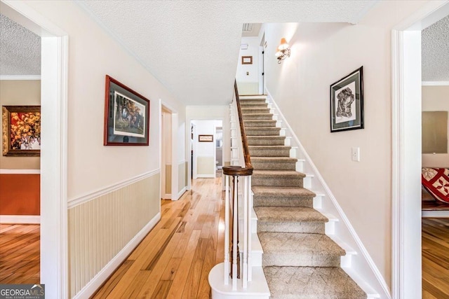 stairs with hardwood / wood-style floors and a textured ceiling