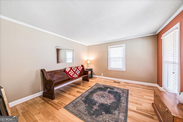 living area featuring ornamental molding, a textured ceiling, and light wood-type flooring