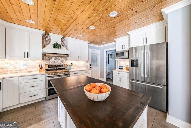 kitchen with white cabinetry, appliances with stainless steel finishes, and custom range hood