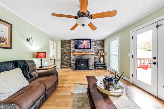 living room with crown molding, a fireplace, light hardwood / wood-style floors, and a textured ceiling