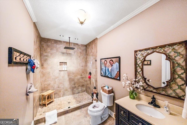 bathroom featuring tile patterned floors, toilet, a tile shower, ornamental molding, and vanity