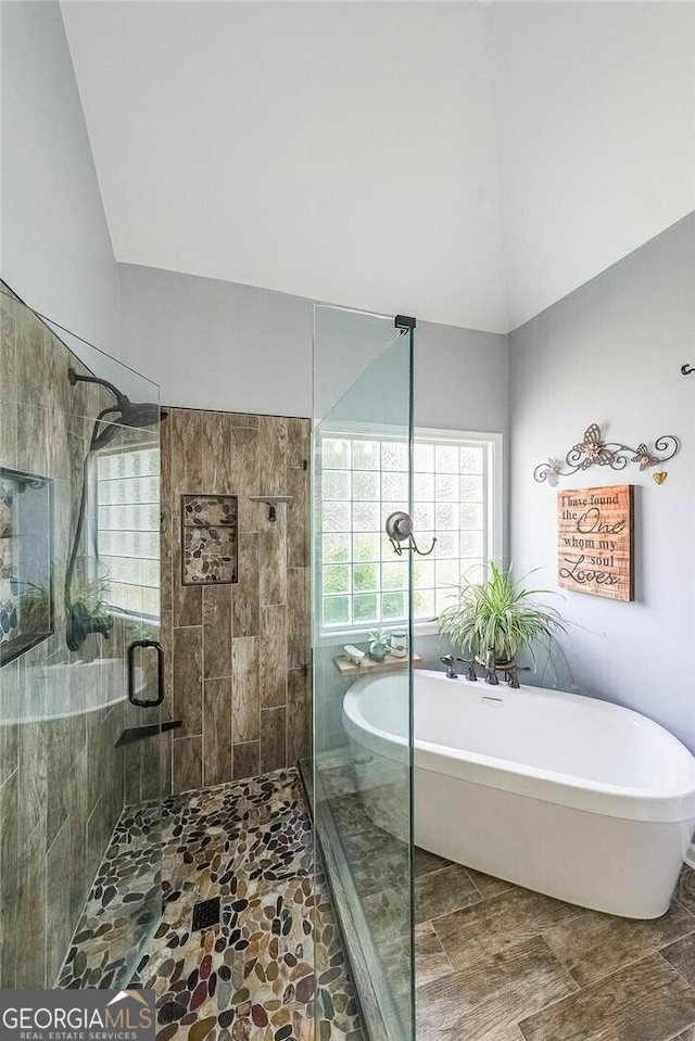 bathroom with shower with separate bathtub and vaulted ceiling