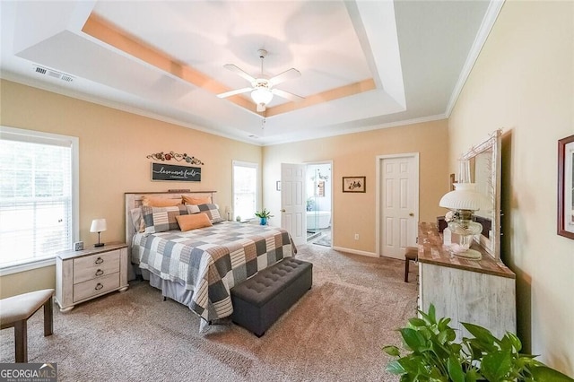 bedroom featuring crown molding, ensuite bath, ceiling fan, a tray ceiling, and light colored carpet