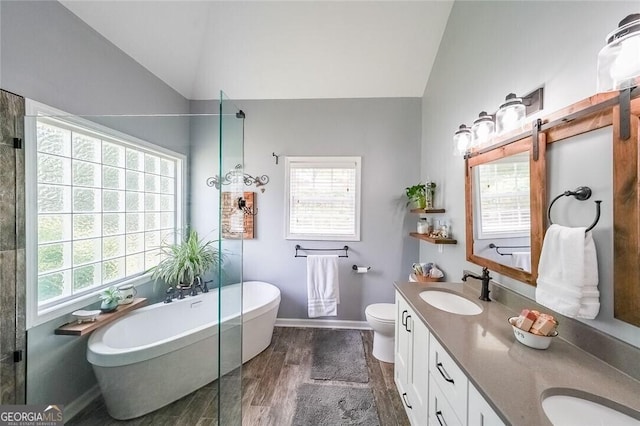 bathroom with a bathing tub, lofted ceiling, hardwood / wood-style flooring, vanity, and toilet