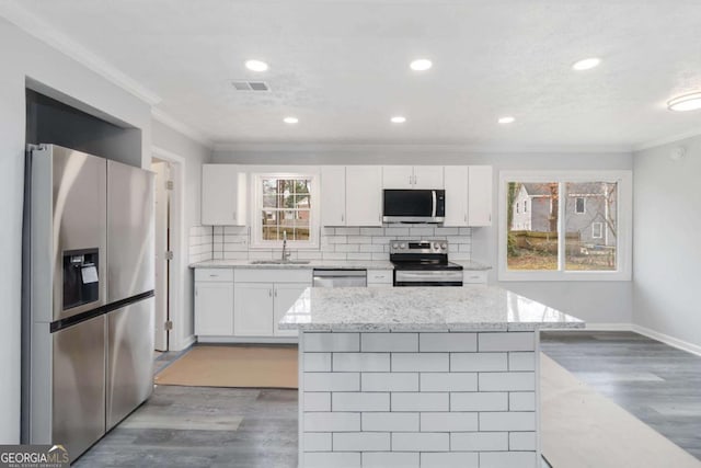 kitchen with white cabinetry, sink, light stone countertops, and appliances with stainless steel finishes