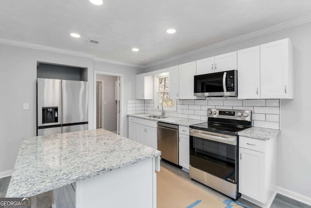 kitchen with stainless steel appliances, white cabinetry, a kitchen island, and backsplash