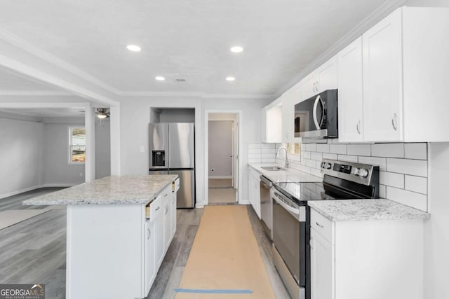 kitchen with sink, white cabinetry, light stone counters, a kitchen island, and stainless steel appliances