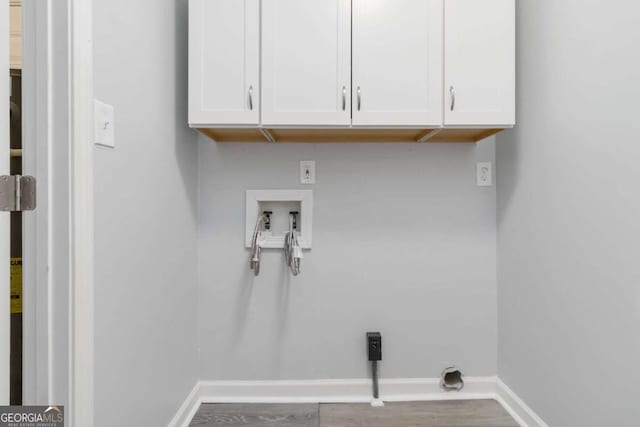 washroom featuring hardwood / wood-style flooring, cabinets, washer hookup, and electric dryer hookup