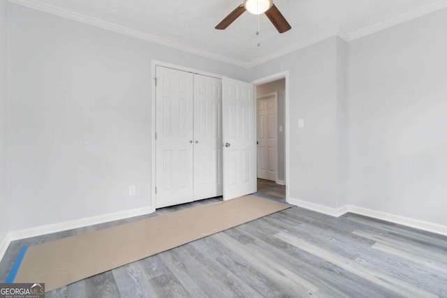 unfurnished bedroom with wood-type flooring, ornamental molding, a closet, and ceiling fan