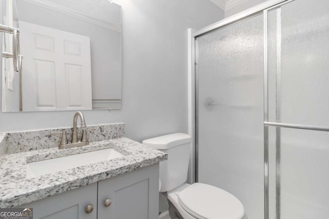 bathroom featuring ornamental molding, vanity, toilet, and a shower with door