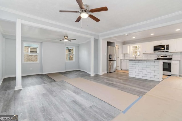 unfurnished living room featuring ornamental molding, sink, and light hardwood / wood-style flooring