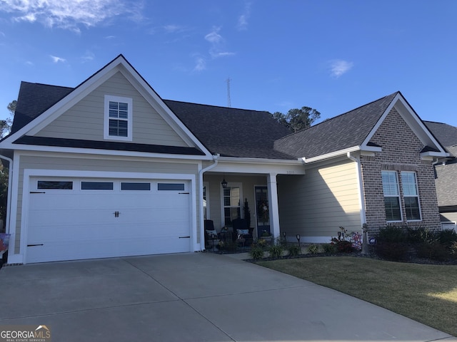 view of front of house featuring a garage, covered porch, and a front lawn