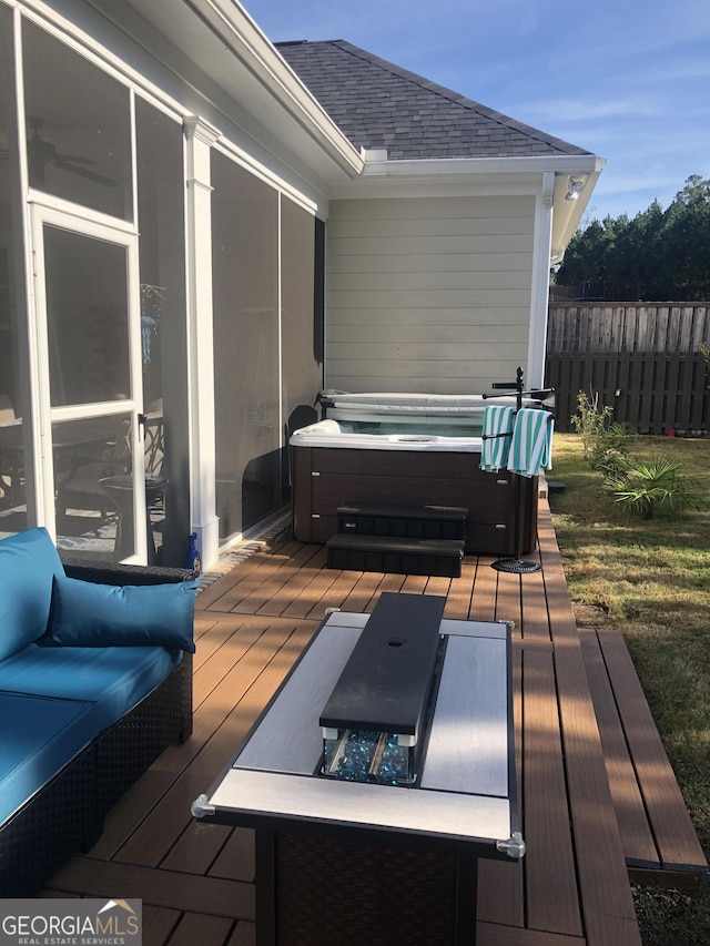 deck with an outdoor hot tub and a lawn