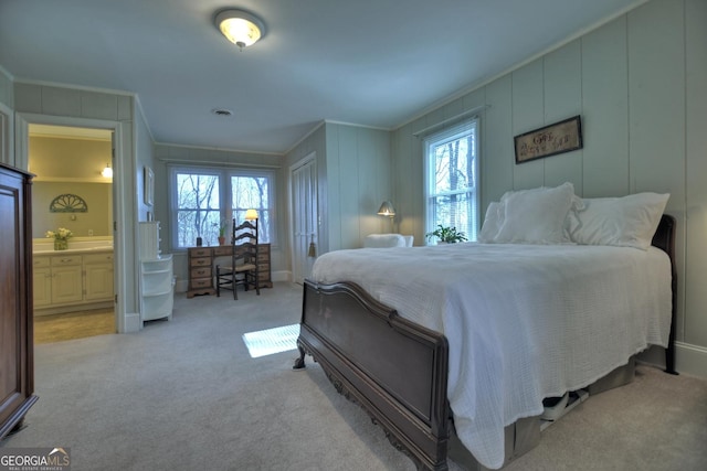 carpeted bedroom featuring ornamental molding and connected bathroom