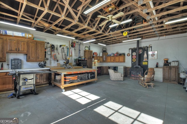 garage featuring a workshop area, ceiling fan, and a wood stove