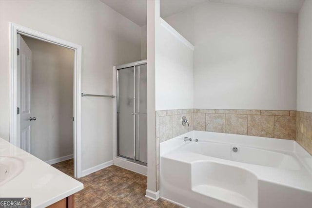 full bathroom featuring a stall shower, baseboards, a garden tub, and vanity