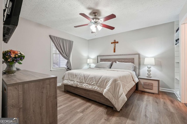 bedroom featuring ceiling fan, hardwood / wood-style flooring, and a textured ceiling