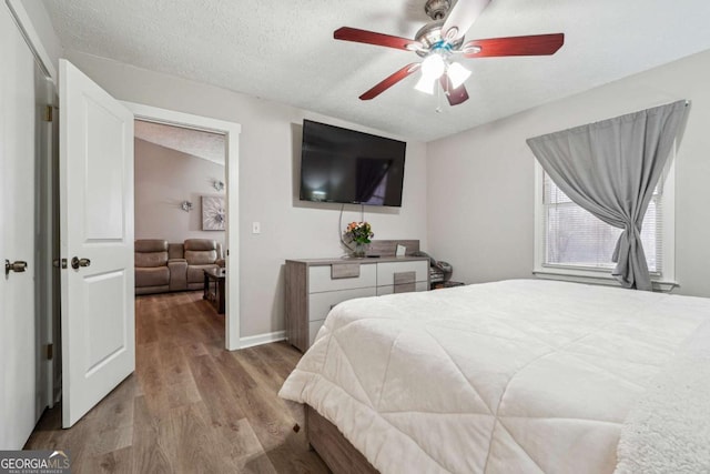 bedroom featuring ceiling fan, light hardwood / wood-style flooring, and a textured ceiling