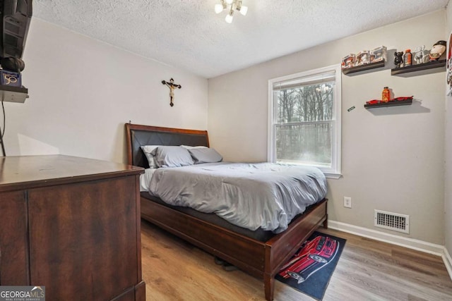 bedroom with a textured ceiling and light hardwood / wood-style floors