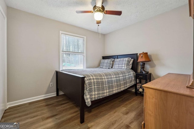 bedroom with ceiling fan, dark hardwood / wood-style flooring, and a textured ceiling