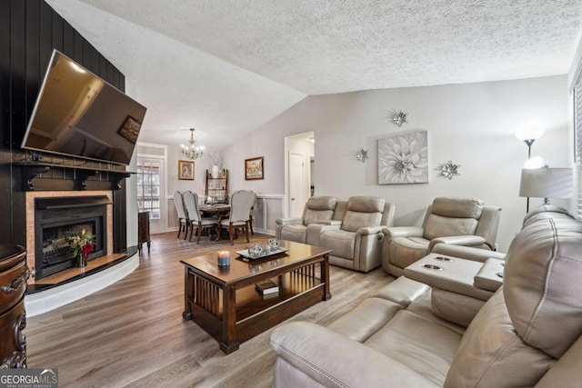 living room featuring hardwood / wood-style flooring, vaulted ceiling, a textured ceiling, and a notable chandelier