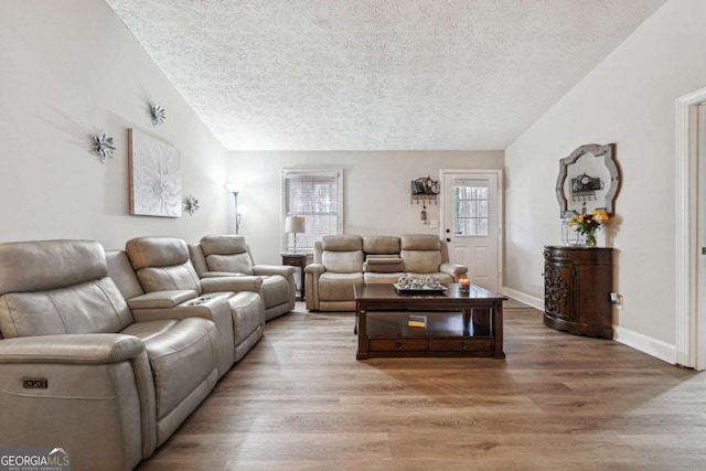 living room with lofted ceiling, hardwood / wood-style floors, and a textured ceiling