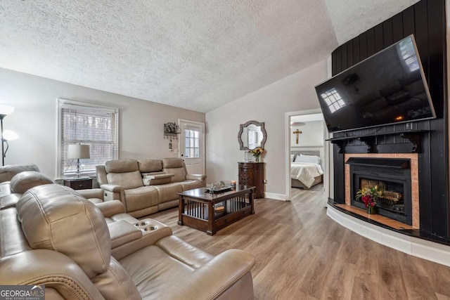 living room with lofted ceiling, light hardwood / wood-style floors, and a textured ceiling