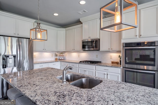 kitchen featuring hanging light fixtures, white cabinetry, appliances with stainless steel finishes, and sink