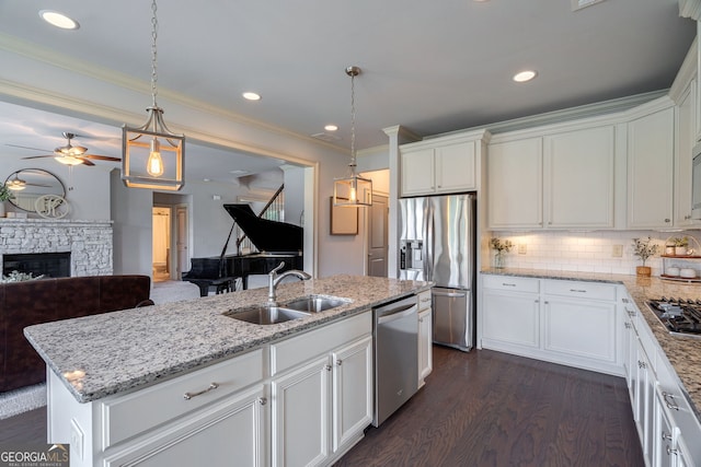 kitchen with an island with sink, appliances with stainless steel finishes, sink, and white cabinets