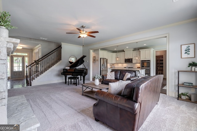 carpeted living room featuring ornamental molding and ceiling fan