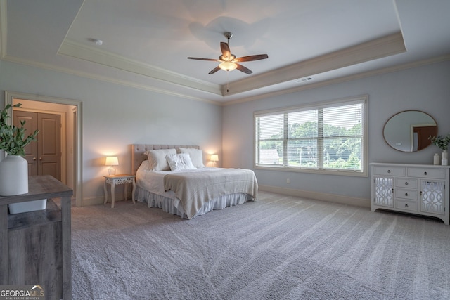 carpeted bedroom with ceiling fan, ornamental molding, and a raised ceiling