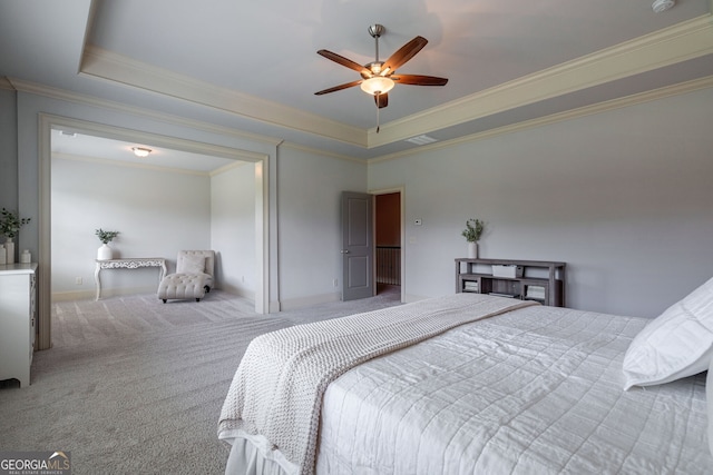 carpeted bedroom with a tray ceiling, ornamental molding, and ceiling fan