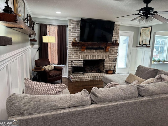 living room with hardwood / wood-style floors, a fireplace, ceiling fan, crown molding, and a textured ceiling