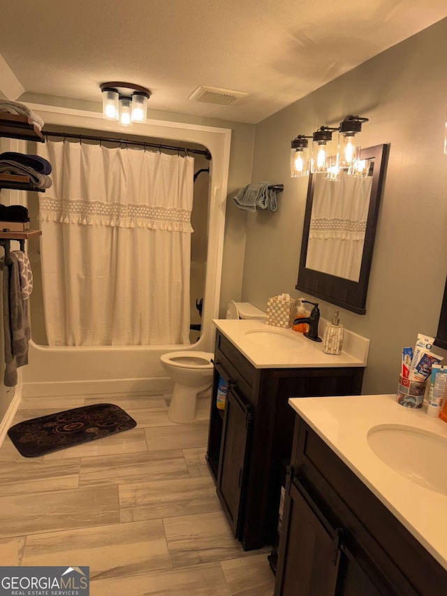 full bathroom with vanity, toilet, a textured ceiling, and shower / bath combo