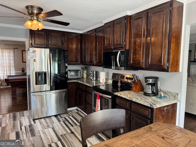 kitchen featuring dark brown cabinetry, appliances with stainless steel finishes, light stone countertops, and ornamental molding