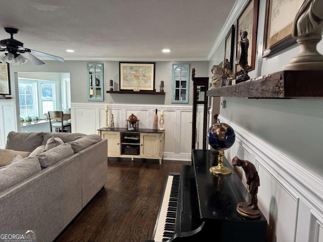 living room with ceiling fan, crown molding, dark wood-type flooring, and a textured ceiling