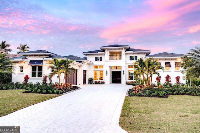 prairie-style home featuring a garage, concrete driveway, a front yard, and stucco siding