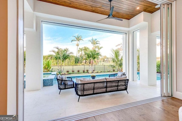 interior space featuring a fenced in pool, fence, outdoor lounge area, and a ceiling fan