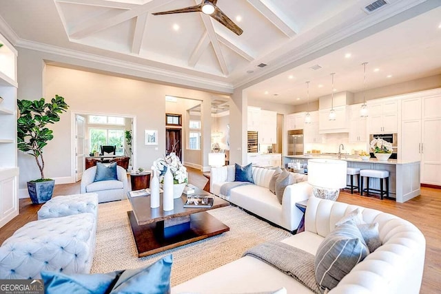 living area featuring beam ceiling, visible vents, light wood-style flooring, and baseboards