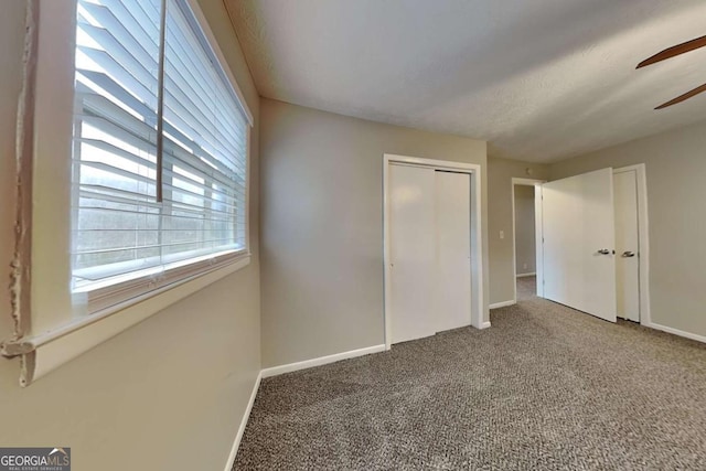 unfurnished bedroom featuring ceiling fan, a closet, carpet, and a textured ceiling